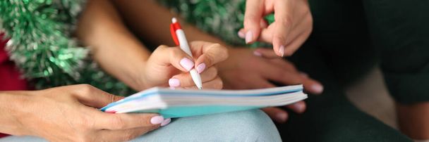 Frau hält Stift in der Hand und schreibt in Notizbuch. - Foto, Bild