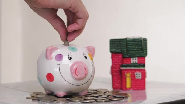 piggy bank business standing on a pile of coins concept. A hand is putting a coin in a lifestyle piggy bank on a yellow background. saving money is an investment for the future. Banking investment. - Footage, Video
