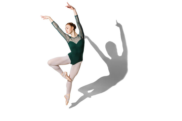 Graceful female ballet dancer posing isolated over white background with shadow. - Photo, Image