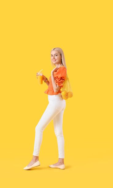 Όμορφη νεαρή γυναίκα με πορτοκάλια και χυμό στο φόντο χρώμα - Φωτογραφία, εικόνα