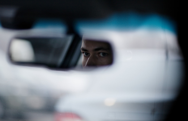 Mann schaut während der Fahrt in den Rückspiegel - Foto, Bild
