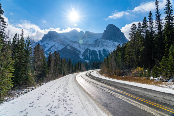 Three Sisters Parkway (Highway 742) en la mañana del día soleado de la temporada de invierno. Cielo azul claro, nevado Monte Lawrence Grassi en el fondo. Canmore, AB, Canadá. - Foto, Imagen