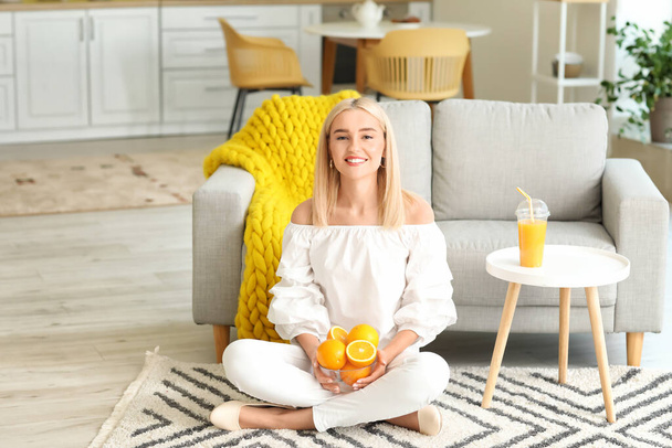 Beautiful young woman with fresh oranges at home - Foto, Imagen