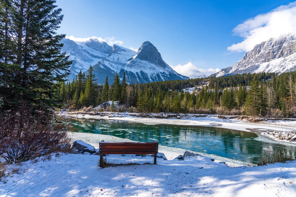 Natural scenery in early winter season sunny day morning. Drift ice floating on Bow River. Clear blue sky, snow capped Mount Lawrence Grassi in background. Landscape in Town Canmore, Alberta, Canada. - Photo, Image