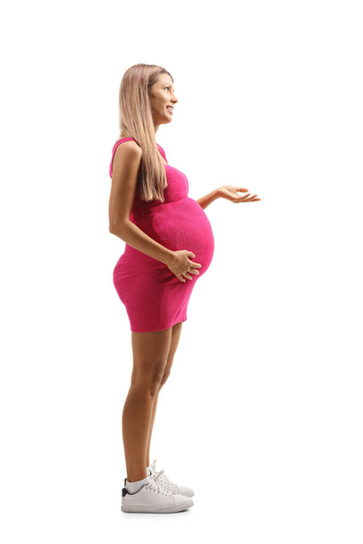 Full length profil záběr mladé těhotné ženy v růžových šatech izolovaných na bílém pozadí - Fotografie, Obrázek
