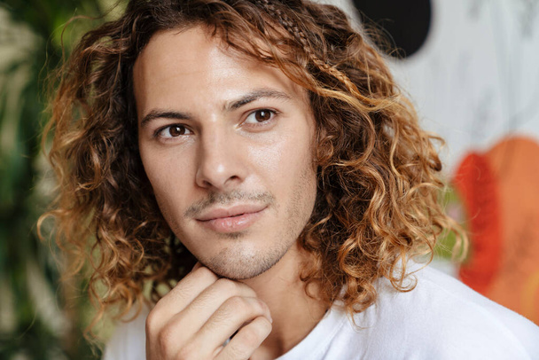 Image of young handsome curly man indoors at home looking aside - Foto, Bild
