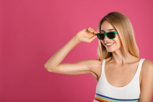 Beautiful woman in stylish sunglasses on pink background. Space for text - Foto, imagen