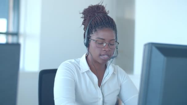 Εστιασμένη Αφροαμερικανός χειριστής σε ακουστικά που μιλάει με τον πελάτη - Πλάνα, βίντεο
