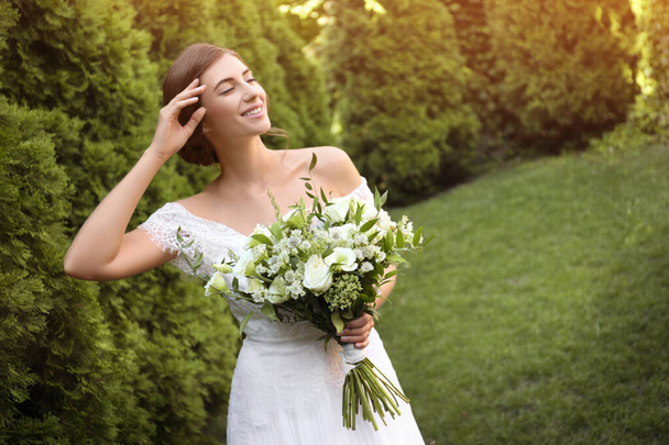Gorgeous bride in beautiful wedding dress with bouquet outdoors - Fotografie, Obrázek