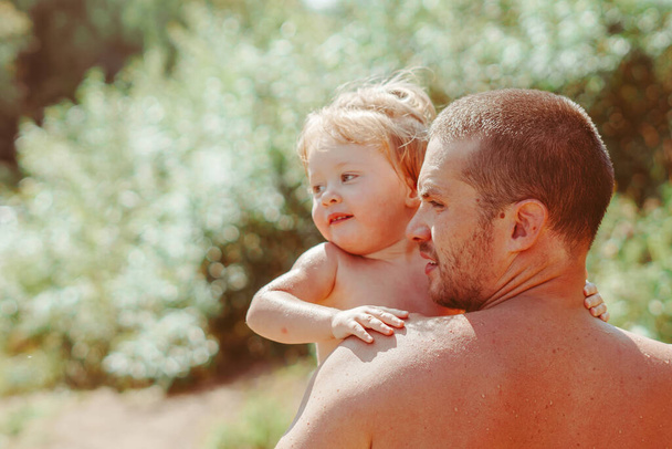 father holds child on hands after swimming in the river - Φωτογραφία, εικόνα