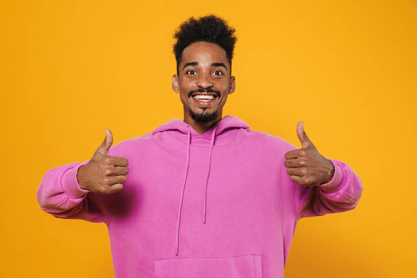 Happy african american guy showing thumbs up and smiling isolated over yellow background - Photo, image
