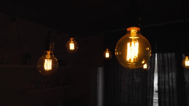 Big vintage incandescent light bulbs hanging in the dark kitchen. Decorative antique edison light bulbs with straight wire. Inefficient filament light bulbs waste electricity. Warm white dimmable, led - Кадры, видео