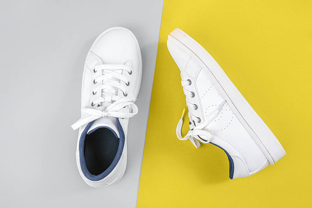 White sports shoes, sneakers with shoelaces on yellow and gray background. Sport lifestyle concept Top view Flat lay. Trendy colors 2021. - Foto, afbeelding