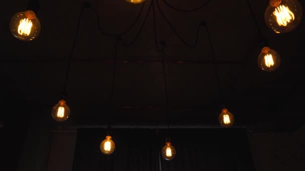 Decorative antique edison light bulbs with straight wire. Big vintage incandescent light bulbs hanging in the dark room. Inefficient filament light bulbs waste electricity. Dimmable, warm white, led - Кадры, видео