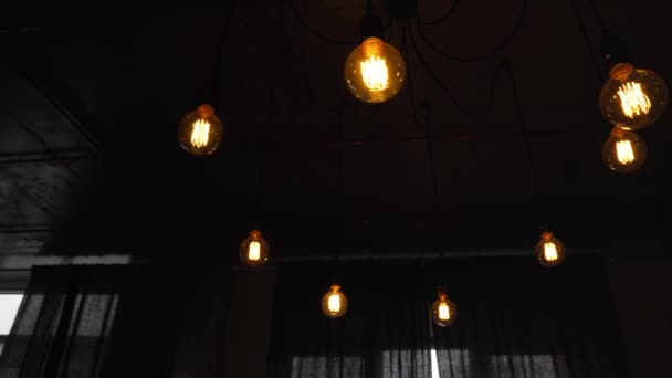 Decoratieve antieke Edison gloeilampen met rechte draad. Grote vintage gloeilampen hangend in de donkere kamer. Inefficiënte gloeilampen verspillen elektriciteit. Dimbaar, warm wit, led - Video