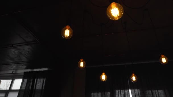 Koriste antiikki edison lamput suoralla johdolla. Iso vintage hehkulamput roikkuu pimeässä huoneessa. Tehottomat hehkulamput tuhlaavat sähköä. Himmennettävä, lämmin valkoinen, johti - Materiaali, video