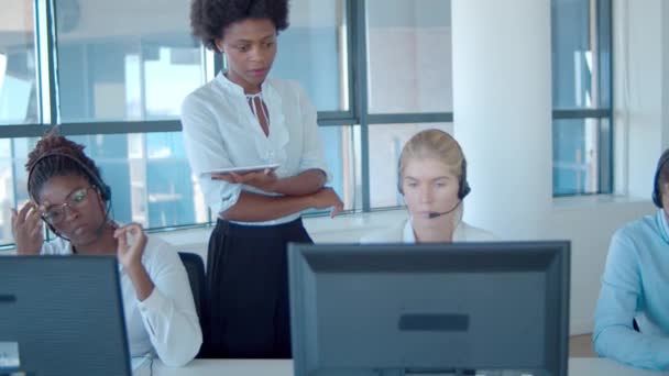 Serieuze vrouwelijke call center coach helpt operator in headset - Video