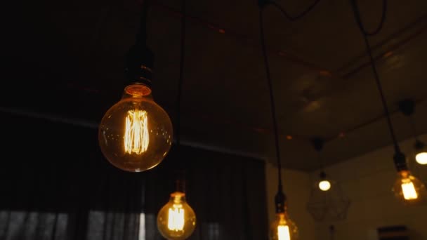 Decorative antique edison light bulbs with straight wire. Big vintage incandescent light bulbs hanging in the dark kitchen. Inefficient filament light bulbs waste electricity. Dimmable warm white, led - Кадры, видео