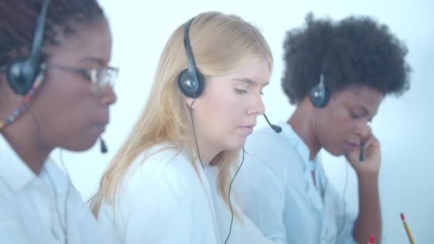 Wiersz różnych operatorów call center w słuchawkach odbierających połączenia - Materiał filmowy, wideo