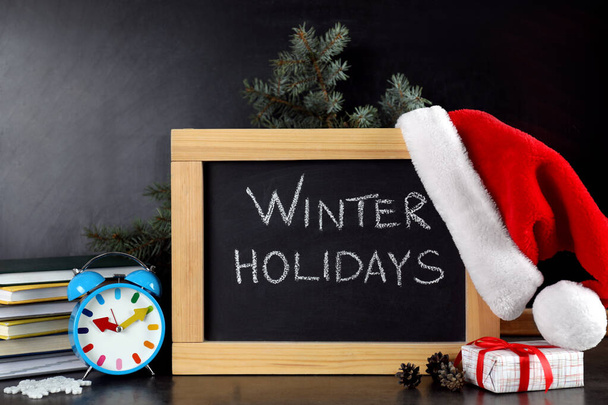 Blackboard with text Winter Holidays and Christmas decor on table - Zdjęcie, obraz