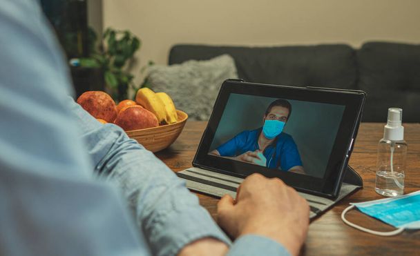 Ο άνθρωπος κάνει βιντεοκλήση με το γιατρό του στην απομόνωση. - Φωτογραφία, εικόνα
