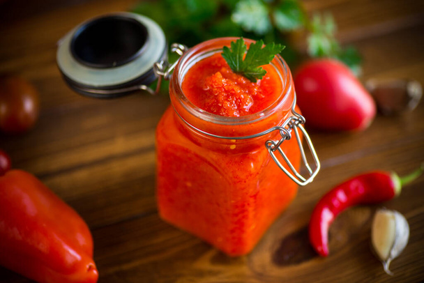 fresh natural homemade sauce made of peppers, tomatoes and other vegetables in a glass jar - Photo, Image