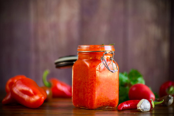 fresh natural homemade sauce made of peppers, tomatoes and other vegetables in a glass jar - Φωτογραφία, εικόνα