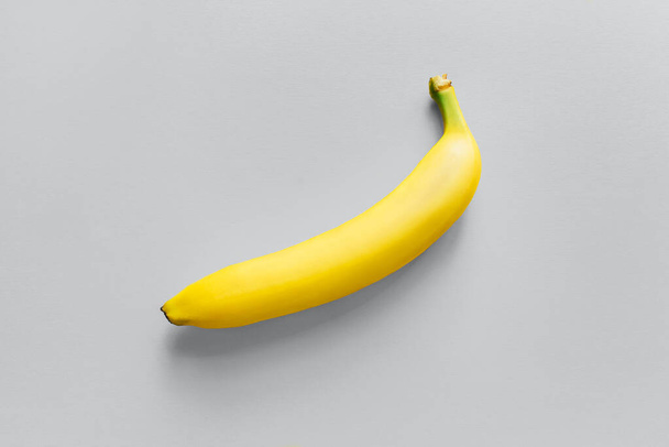 One yellow banana on a gray background. - Foto, afbeelding