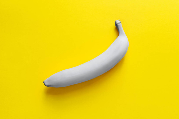 One gray banana on a yellow background. - Φωτογραφία, εικόνα