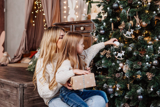 Little girl and her mother decorate a Christmas tree for New Year - Photo, Image