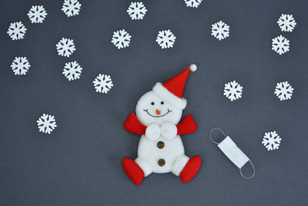Figurine de bonhomme de neige et masques médicaux sur fond gris. Des brindilles d'épinette. Nouvel An, carte de Noël.Copier spase. focus sélectif - Photo, image