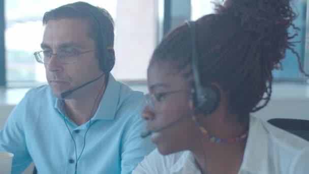 Diverse Callcenter-Betreiber in Headsets diskutieren Anruf - Filmmaterial, Video