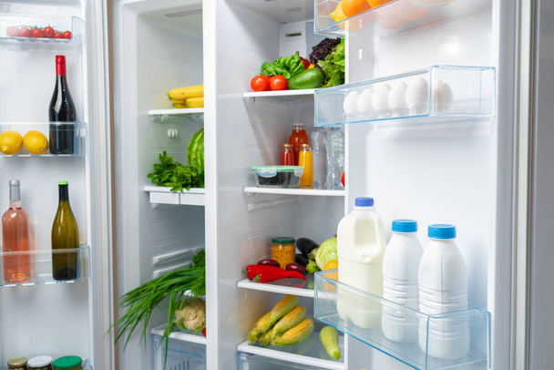Open fridge full of fruits, vegetables and drinks - Фото, зображення