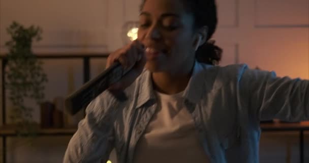 Mujer cantando canción con control remoto como micrófono y bailando en casa - Metraje, vídeo