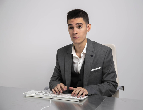 Νεαρός επιχειρηματίας με κοστούμι χρησιμοποιώντας πληκτρολόγιο υπολογιστή στην εργασία - Φωτογραφία, εικόνα