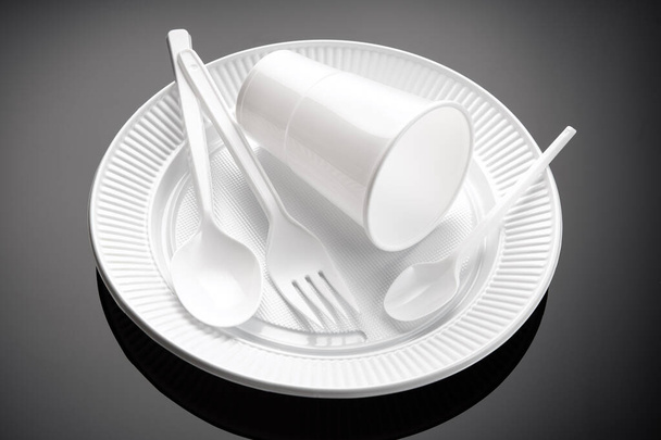 Plastic vaatwerk. Witte beker, bord, vork en lepel Wegwerpafval van kunststof - Foto, afbeelding