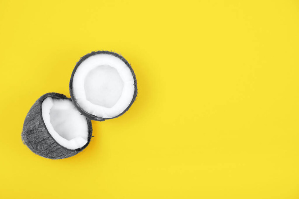 Top view of halved ripe gray colored coconut on bright yellow background. Trendy colors 2021 year. Summer concept. Minimal flat lay.Place for text - 写真・画像