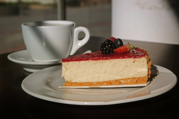 vanilla cheesecake with berries with a cup of cappuccino on the background - Foto, Bild