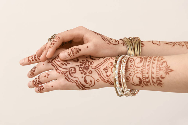 Schöne weibliche Hände mit Henna-Tätowierung auf hellem Hintergrund - Foto, Bild