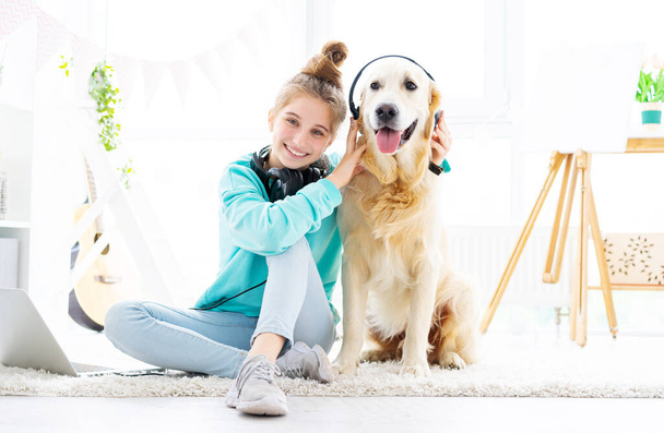 Happy girl holding headphones on dog - 写真・画像