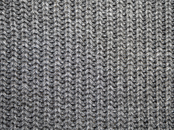 Texture of wool knitted fabric from yarn, closeup. Image for the background, wallpaper. wool carpet or sweater. Gray texture. Modern design. - Photo, Image