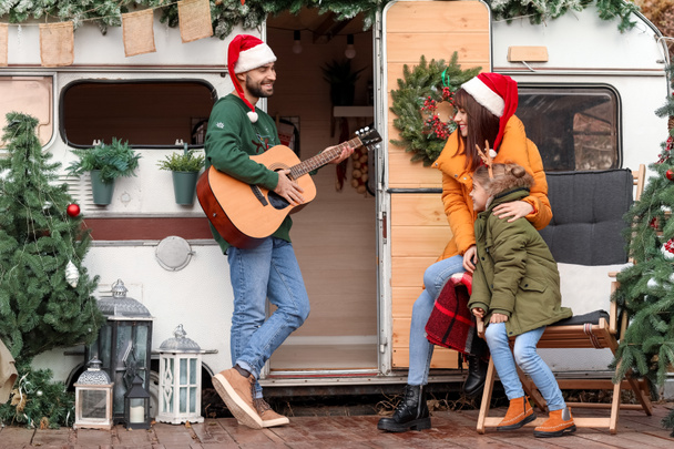 Happy family with guitar outdoors on Christmas eve - 写真・画像