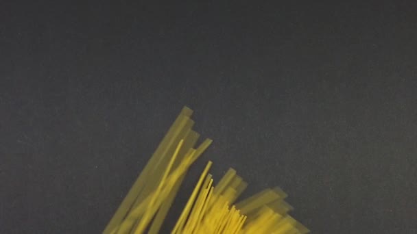 La mano de mujer pone sobre la mesa los espaguetis secos de pasta. Movimiento lento sobre fondo negro - Metraje, vídeo