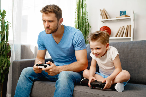 Apa és a kisfia együtt videojátékoznak otthon. - Fotó, kép