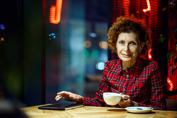 Oudere vrouw die tabletten gebruikt in een café. Volwassen vrouw ontspannen in een restaurant met tablet pc. Oudere vrouwen gebruiken digitale tabletten in de coffeeshop. Technologie, ouderdom en mensen concept. Volwassen student. - Foto, afbeelding