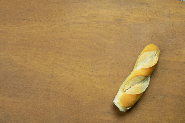 Single stripped bread on wooden table - Foto, Imagen