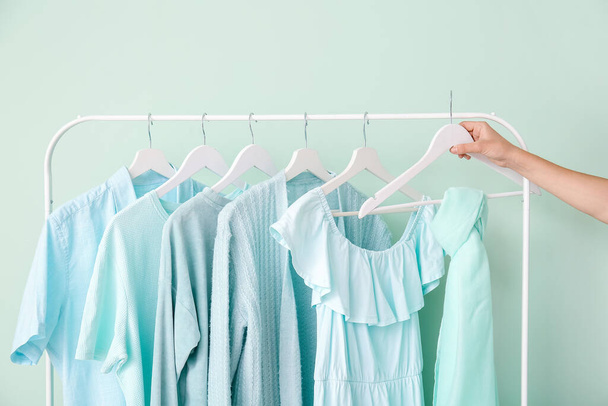 Female hand and rack with clothes near color wall - 写真・画像
