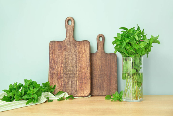 Fresh mint and wooden board on kitchen table - Фото, зображення