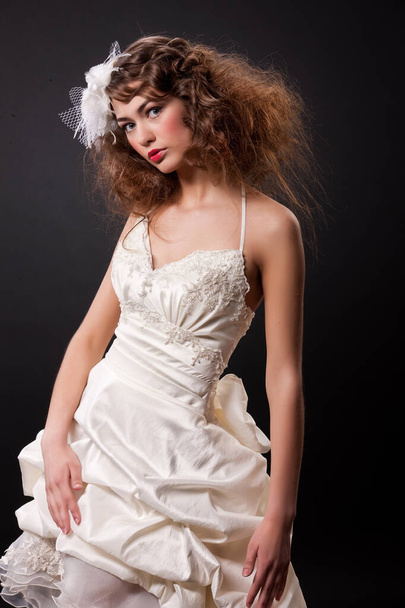 Young beautiful woman in a fashionable wedding dress on a black background - Fotoğraf, Görsel
