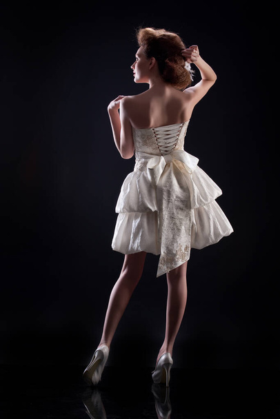 Young woman in wedding dress on a black background - Foto, Imagen